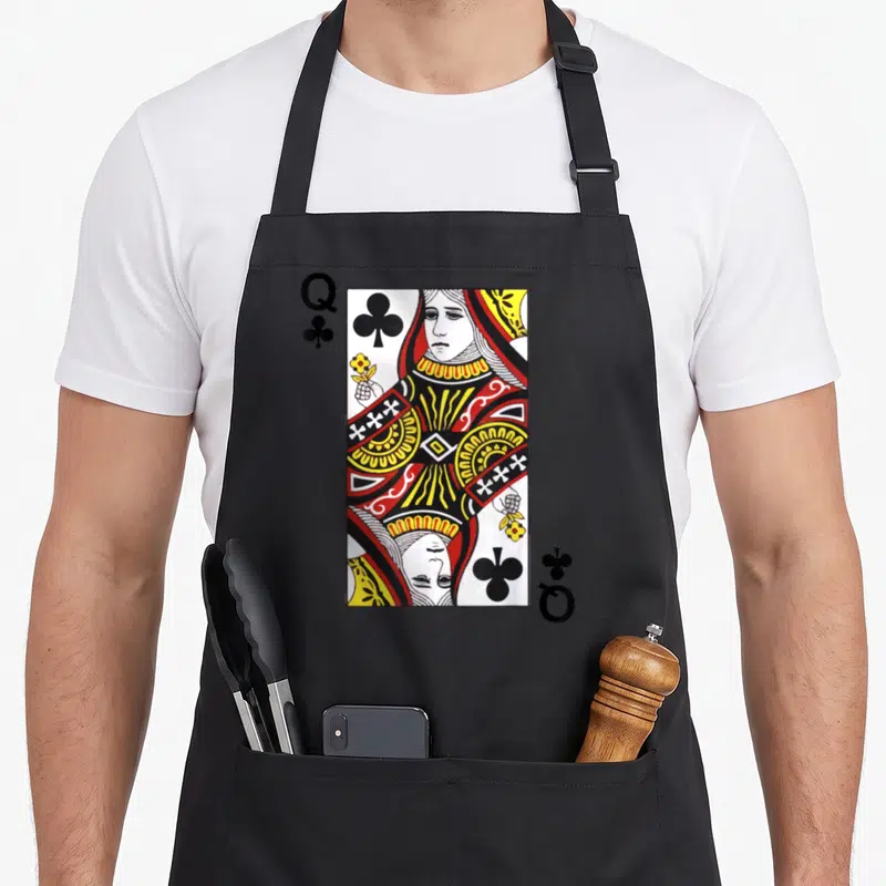 Blackjack queen apron - Queen of Clubs playing card illustration with Q and club symbols in white red yellow and black — shown on a black cotton canvas apron against a white background