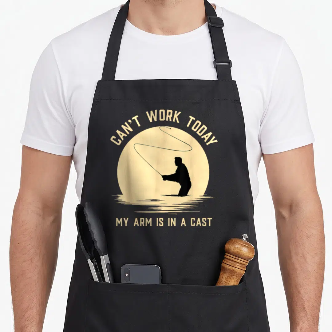 Today fishing aprons - Beige sun circle with black fisherman silhouette casting rod, arched text above, straight text — shown on a black cotton canvas apron against a white background