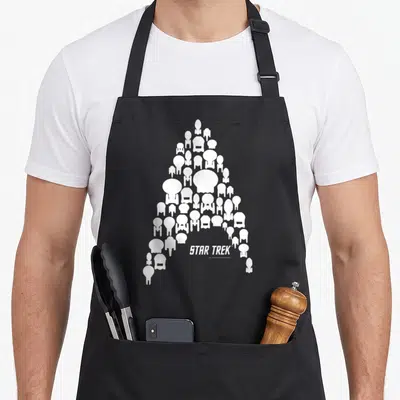 Federation star apron - White Starfleet insignia made of small spaceship silhouettes with STAR TREK text below — shown on a black cotton canvas apron against a white background