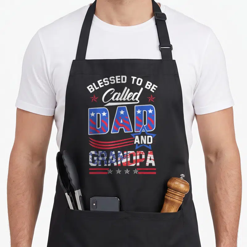Blessed grandpa apron - Stacked text Blessed to be Called Dad and Grandpa with red white and blue flag patterns — shown on a black cotton canvas apron against a white background