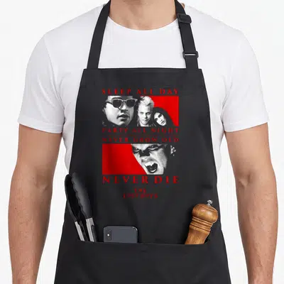 Lost halloween apron - Red text SLEEP ALL DAY PARTY ALL NIGHT stacked with grey vampire portraits on red panels — shown on a black cotton canvas apron against a white background