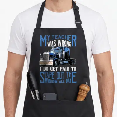 Teacher truck apron - My Teacher Was Wrong text surrounding blue semi-truck illustration — shown on a black cotton canvas apron against a white background