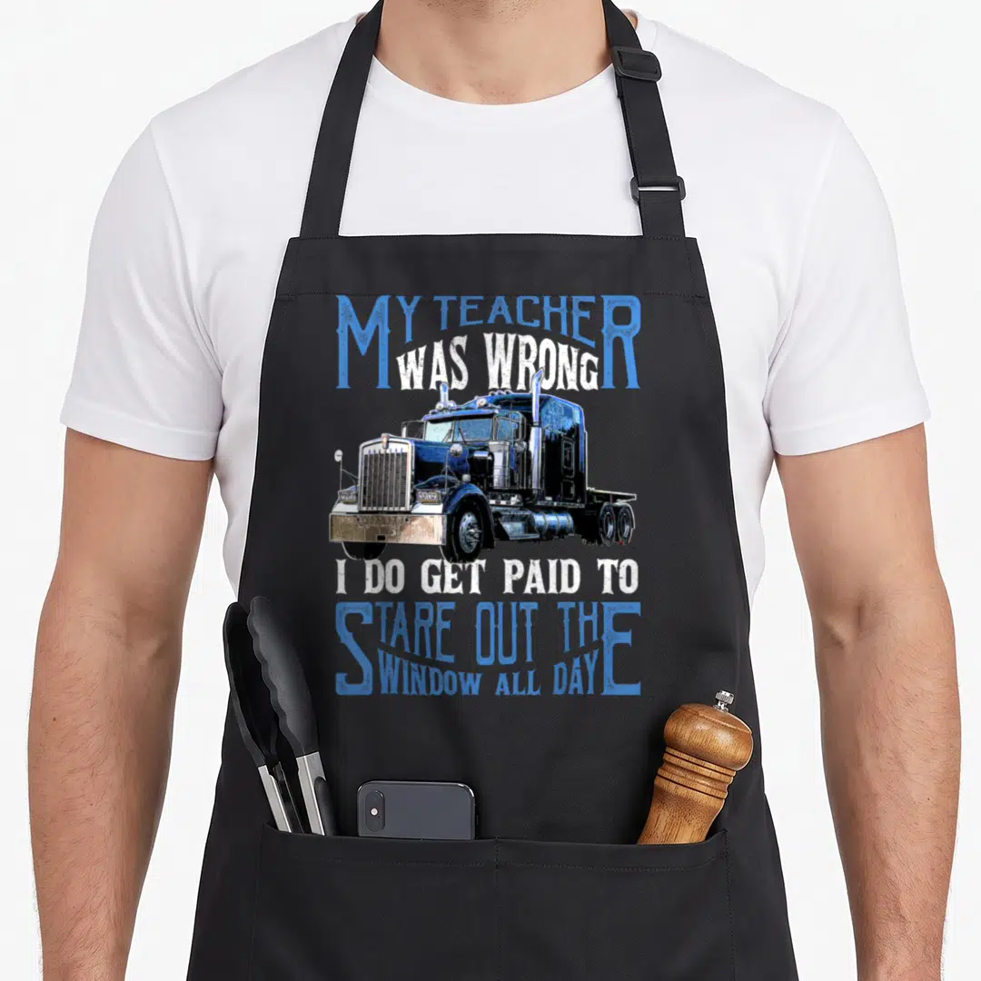 Teacher truck apron - My Teacher Was Wrong text surrounding blue semi-truck illustration — shown on a black cotton canvas apron against a white background