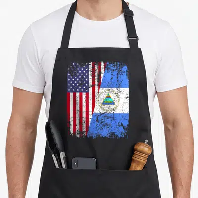 Nicaraguan american flag apron - Merged USA and Nicaragua flags with distressed red white blue print and Republica de — shown on a black cotton canvas apron against a white background