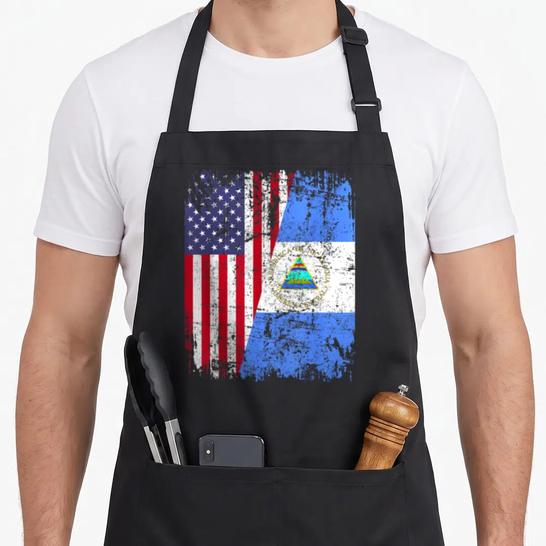 Nicaraguan american flag apron - Merged USA and Nicaragua flags with distressed red white blue print and Republica de — shown on a black cotton canvas apron against a white background
