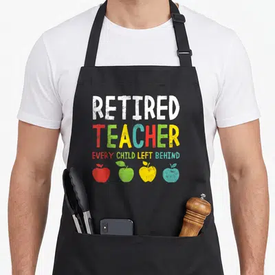 Left teachers apron - Distressed text reading Retired Teacher Every Child Left Behind above four red, green, yellow — shown on a black cotton canvas apron against a white background