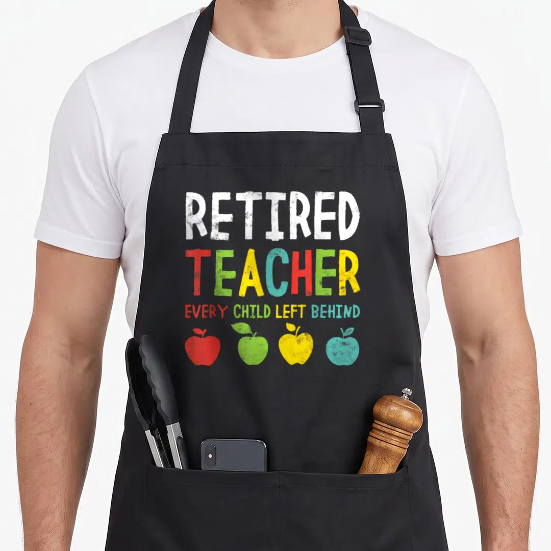 Left teachers apron - Distressed text reading Retired Teacher Every Child Left Behind above four red, green, yellow — shown on a black cotton canvas apron against a white background
