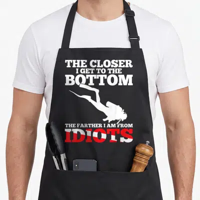 Flag dive diving apron - Scuba diver silhouette between text with red and white striped IDIOTS letters — shown on a black cotton canvas apron against a white background