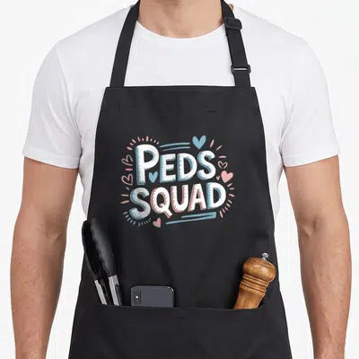 Ped squad nurse apron - Stacked Peds Squad text with white blue and pink hearts and dots — shown on a black cotton canvas apron against a white background