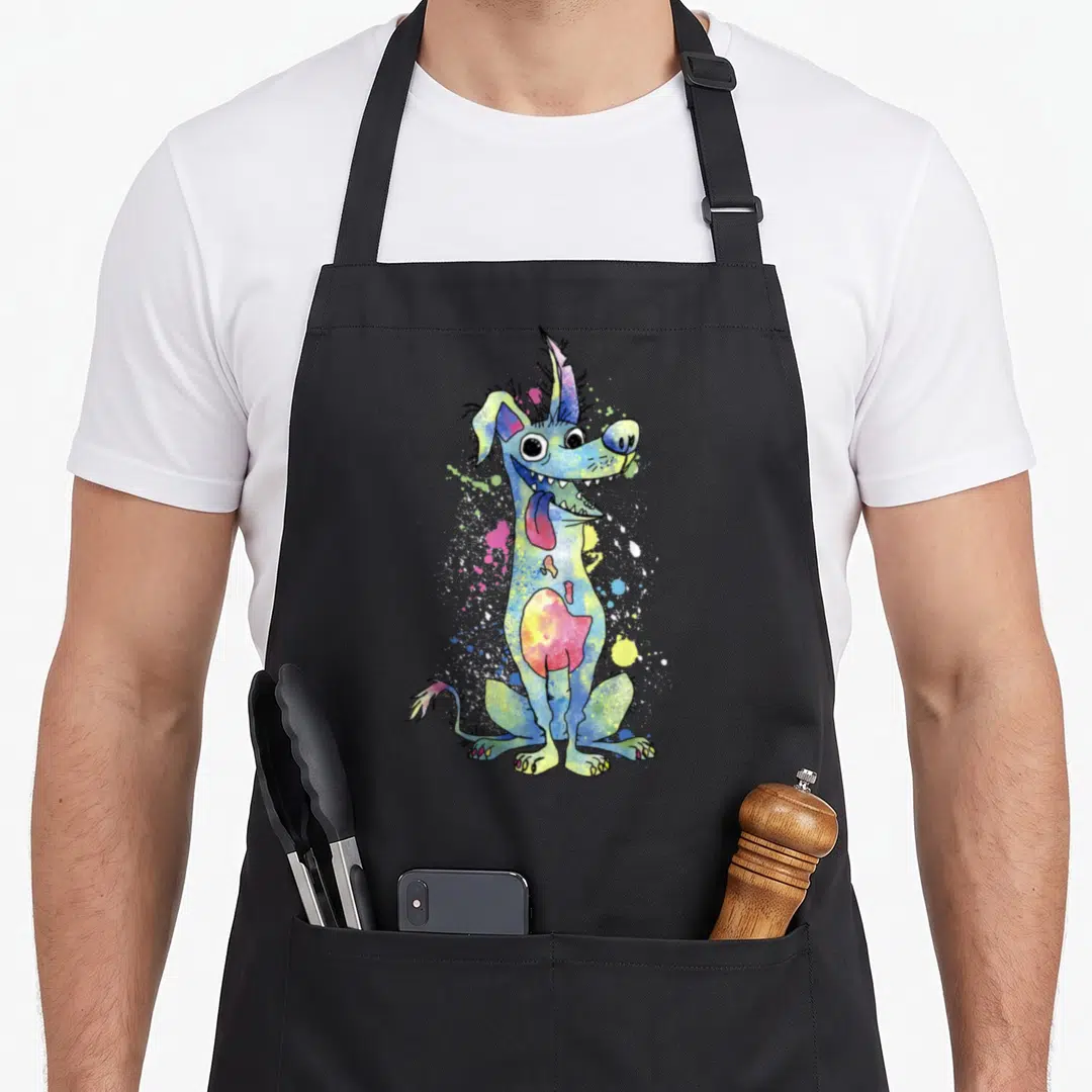 Dante cocoon apron - Cartoon dog in blue yellow pink green with paint splatters on black apron — shown on a black cotton canvas apron against a white background