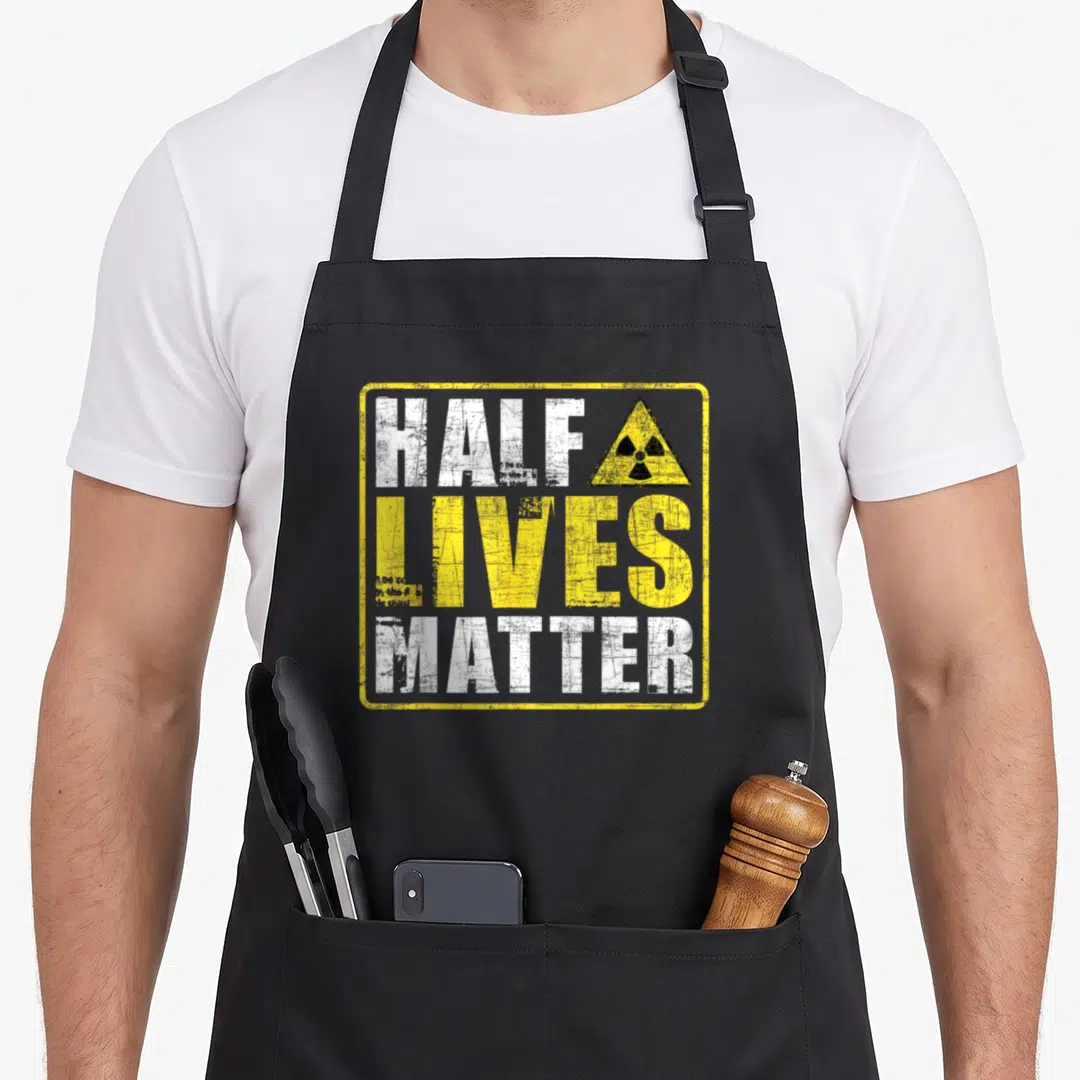 Live engineering apron - Half Lives Matter text with yellow radiation symbol on black apron — shown on a black cotton canvas apron against a white background