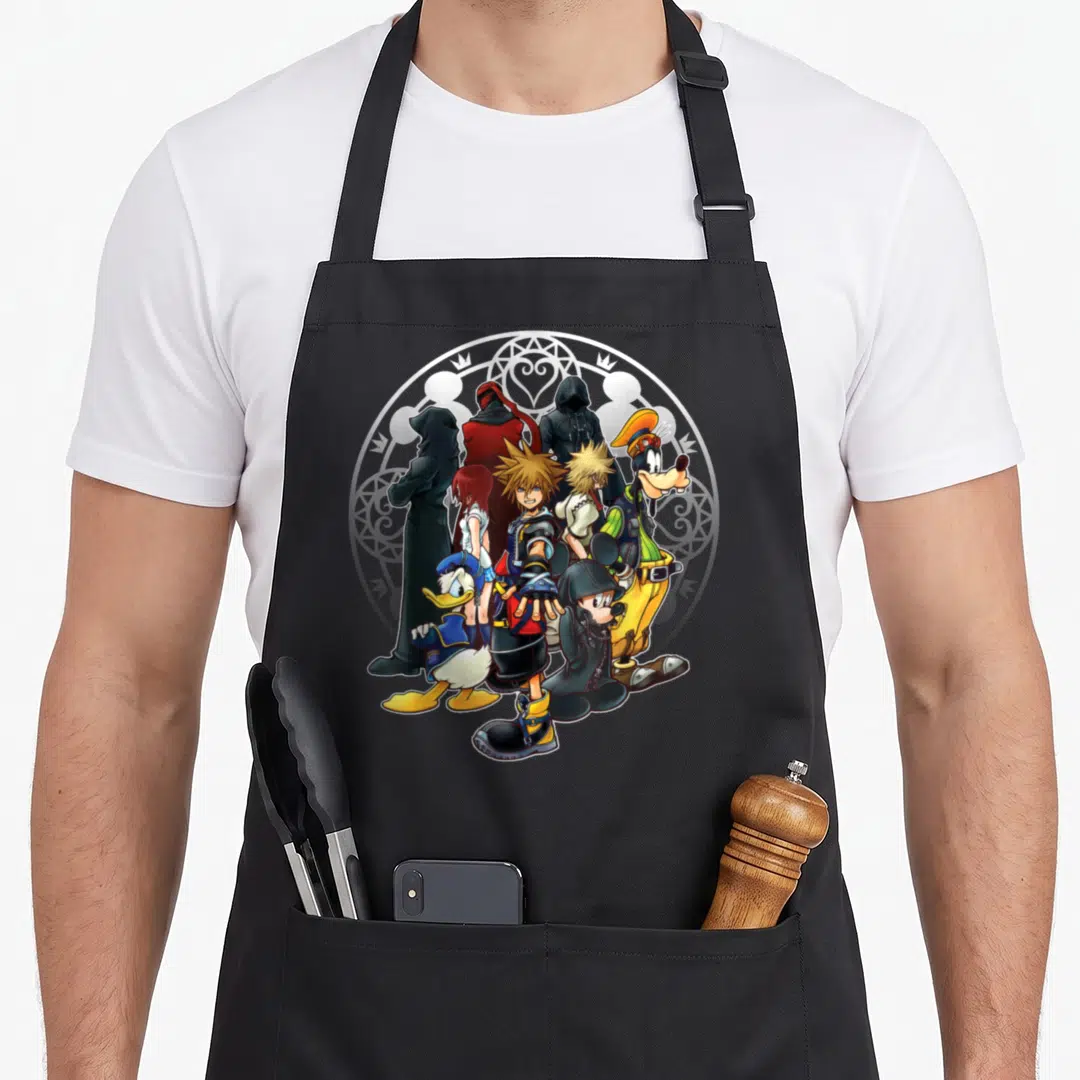Dark of squad apron - Sora and allies in cartoon pyramid cluster before white emblem with black blue yellow details — shown on a black cotton canvas apron against a white background