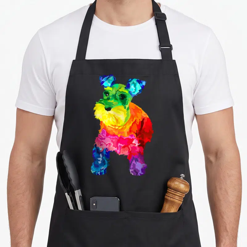 Colorful miniature schnauzer apron - Multicolored watercolor miniature schnauzer dog in blue, green, yellow, orange — shown on a black cotton canvas apron against a white background