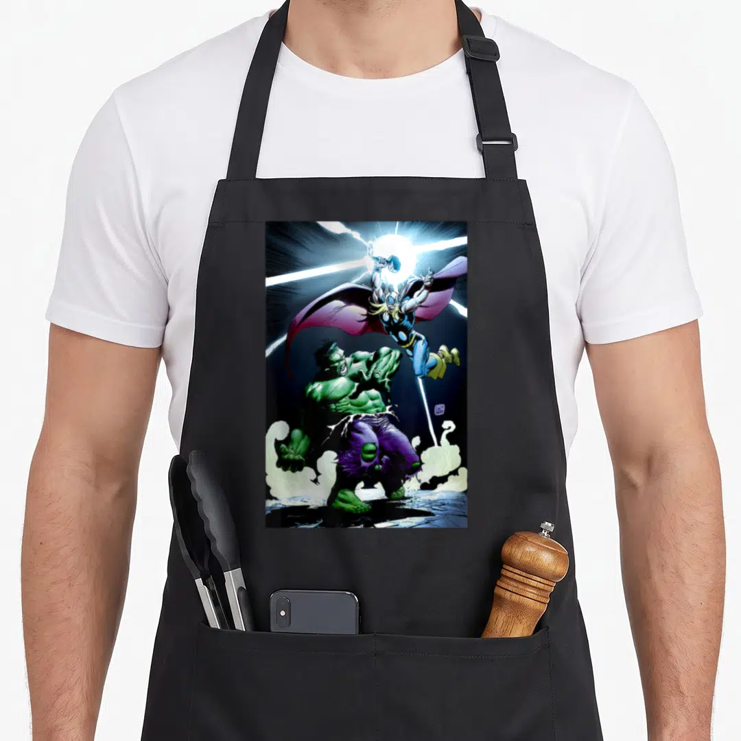Battle universe apron - Thor leaping with hammer above green Hulk standing in purple pants and smoke — shown on a black cotton canvas apron against a white background