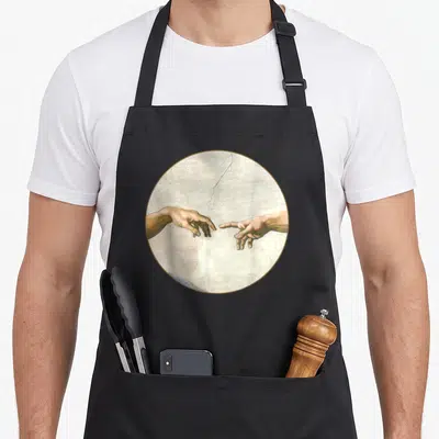 Adam michelangelo apron - Two hands reaching toward each other inside a gold circular frame on beige background — shown on a black cotton canvas apron against a white background