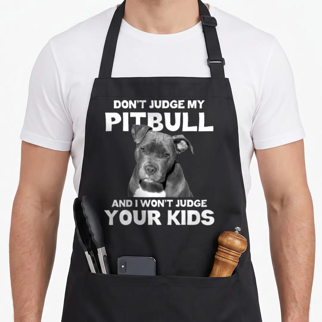 Judge dog apron - Photo of pitbull head with Don't Judge My Pitbull text above and below — shown on a black cotton canvas apron against a white background