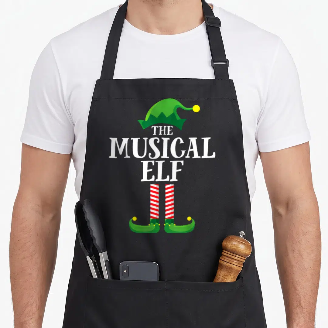 Musical christmas elf apron - Green elf hat, white stacked text, red white striped legs, green shoes — shown on a black cotton canvas apron against a white background