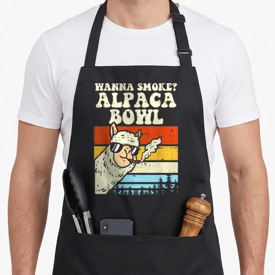 Smoke alpaca apron - Retro alpaca wearing sunglasses smoking in front of orange, yellow, and blue horizontal stripes — shown on a black cotton canvas apron against a white background