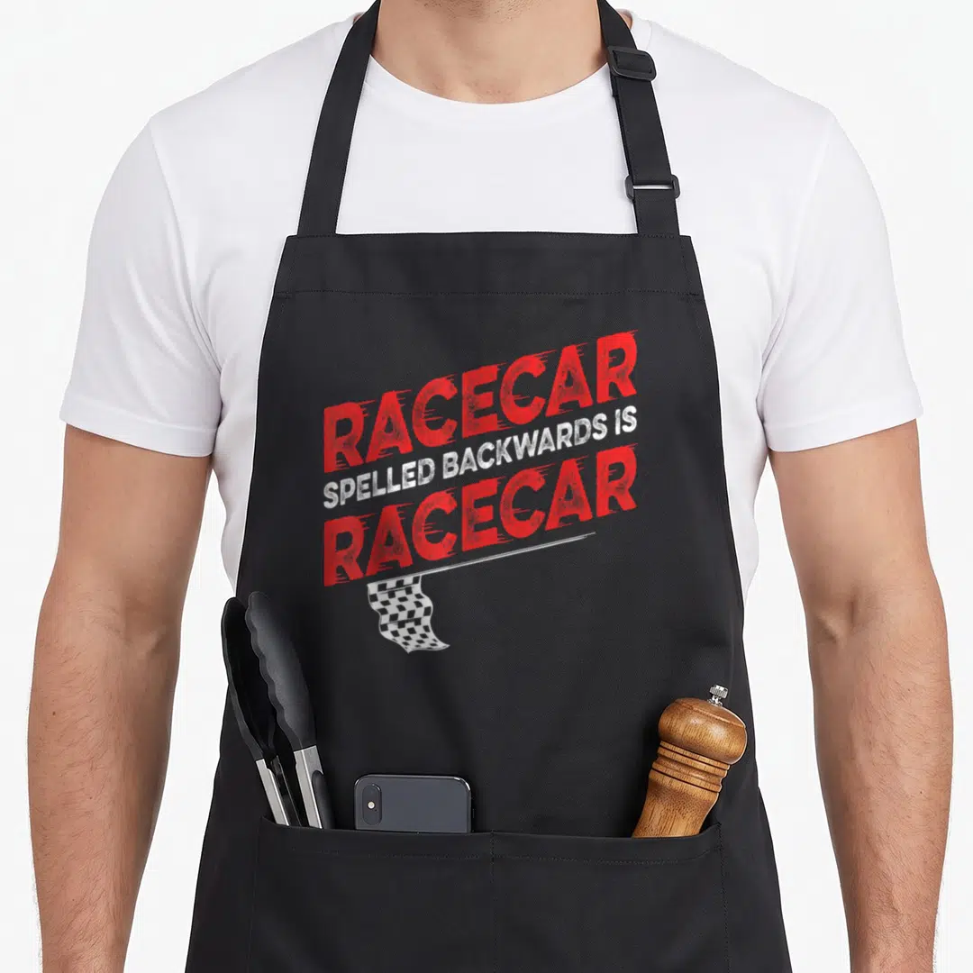 Spelled car apron - Distressed red text reading Racecar spelled backwards is Racecar above a checkered flag on black — shown on a black cotton canvas apron against a white background