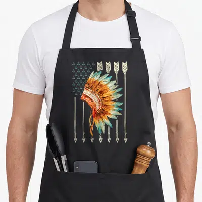 Native american flag apron - Watercolor headdress over six arrows with star grid in orange teal beige yellow — shown on a black cotton canvas apron against a white background