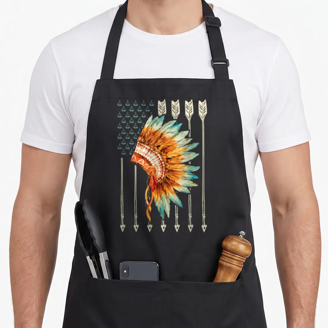 Native american flag apron - Watercolor headdress over six arrows with star grid in orange teal beige yellow — shown on a black cotton canvas apron against a white background