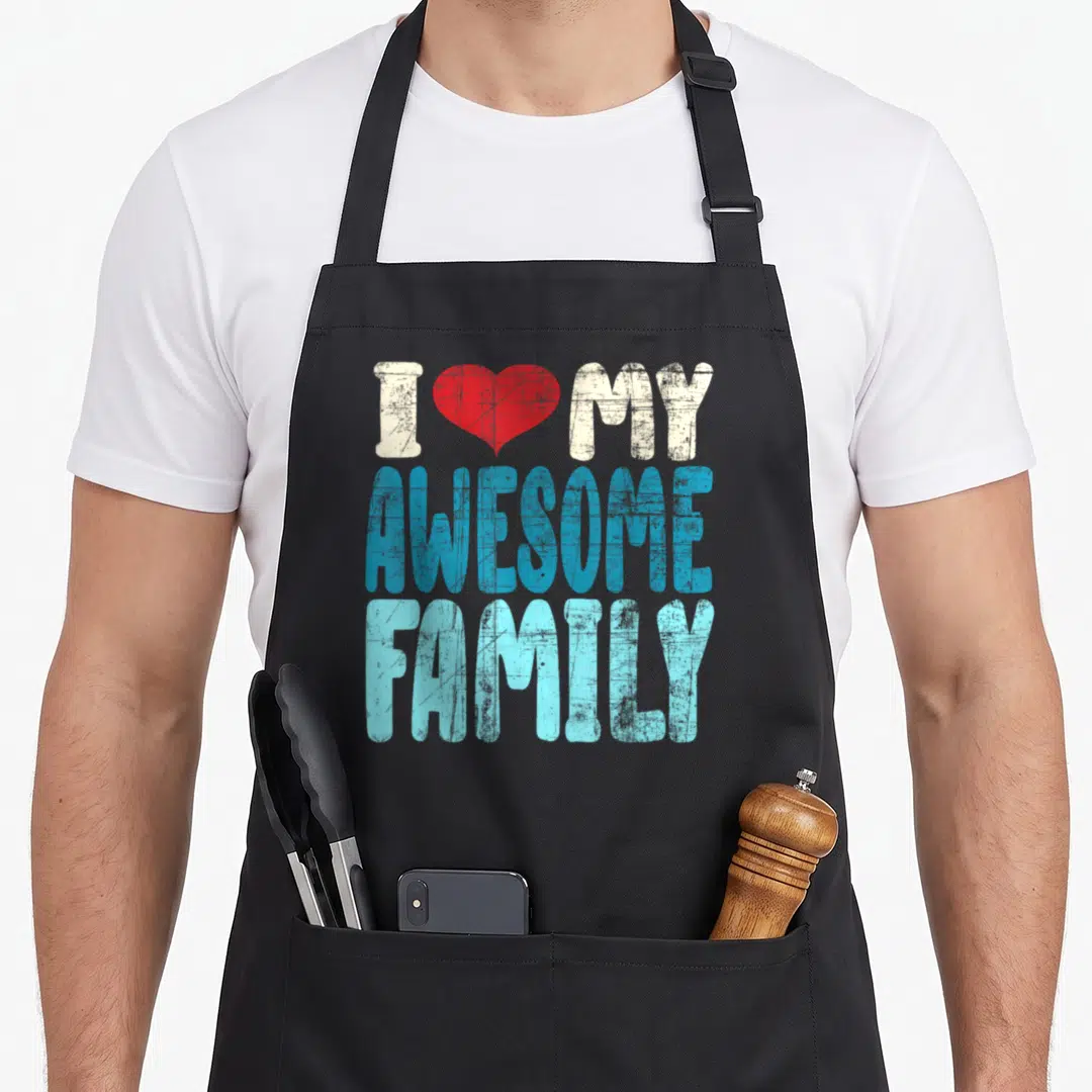 Distressed gathering apron - Red heart between I and MY with stacked AWESOME FAMILY text in distressed blue — shown on a black cotton canvas apron against a white background
