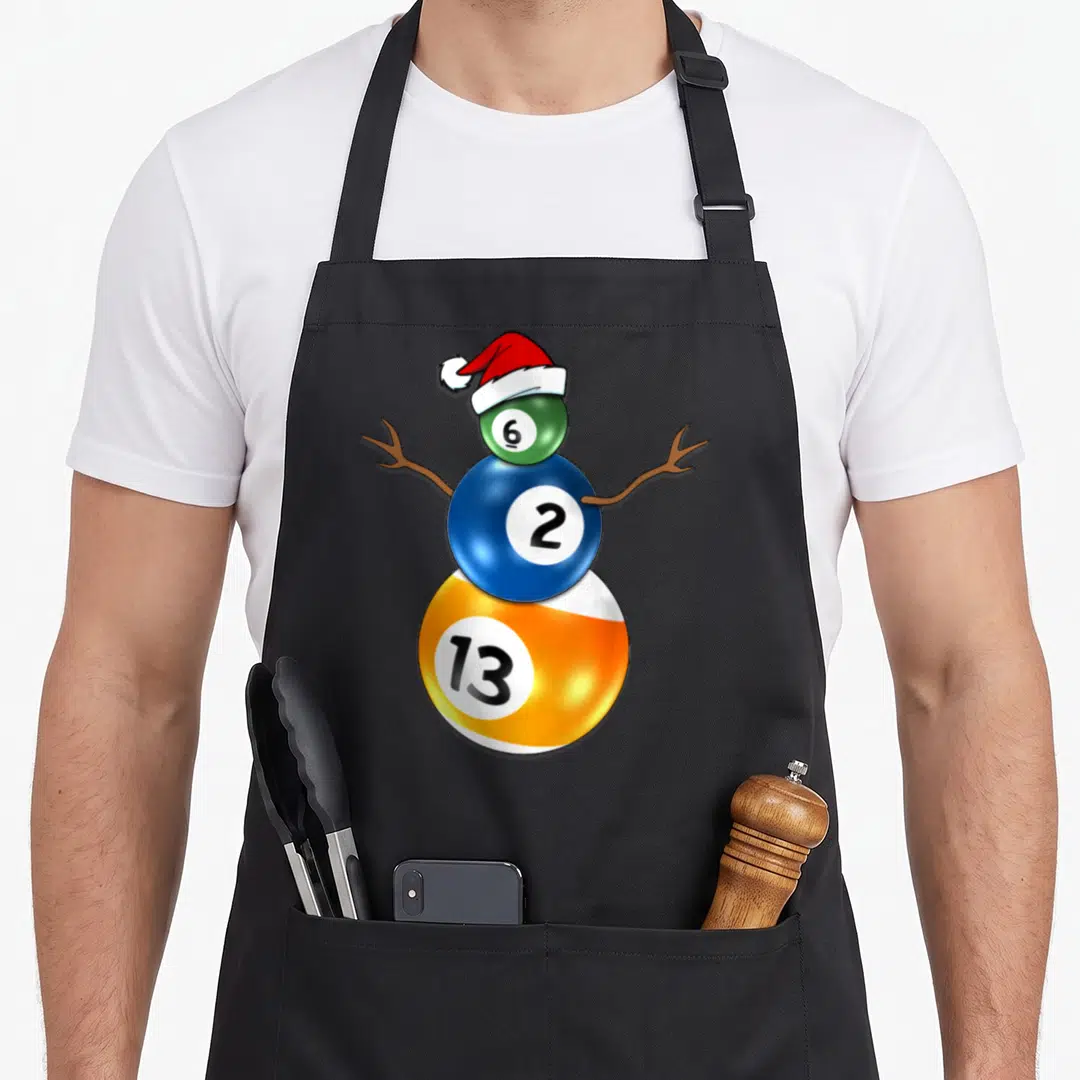 Billiard snowman apron - Cartoon snowman formed by stacked green 6, blue 2, and orange 13 billiard balls wearing — shown on a black cotton canvas apron against a white background