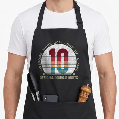 Digit 10th double apron - Retro striped number 10 inside white circle with AWESOME SINCE 2014 and OFFICIAL DOUBLE — shown on a black cotton canvas apron against a white background