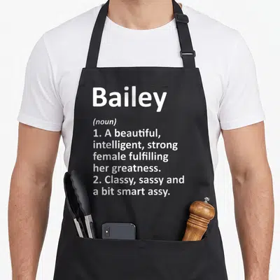 Meaning crew apron - White text reading Bailey noun definition listing beautiful intelligent strong female class sassy — shown on a black cotton canvas apron against a white background