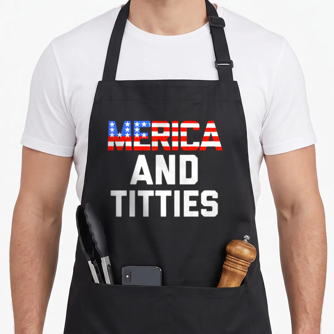 Funny merica 4th of july apron - Stacked red white and blue text reading MERICA AND TITTIES in bold font — shown on a black cotton canvas apron against a white background