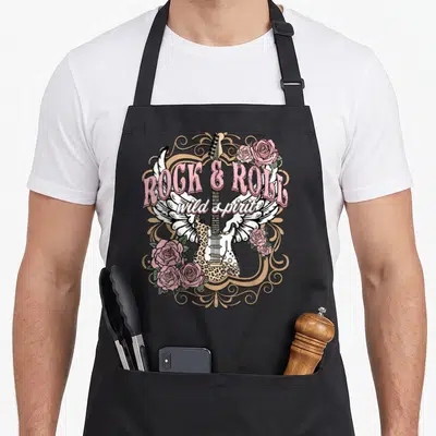 Funny rock girl apron - Retro electric guitar with wings, pink roses, and arched text in pink and tan — shown on a black cotton canvas apron against a white background
