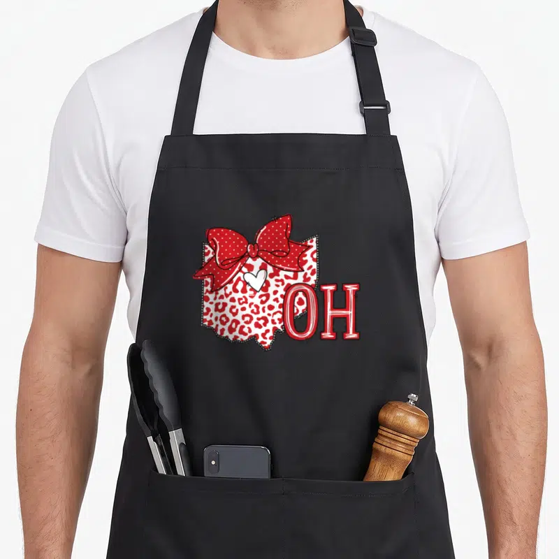 Sister pride apron - Ohio map with red leopard print, polka dot bow, white heart, and OH text — shown on a black cotton canvas apron against a white background
