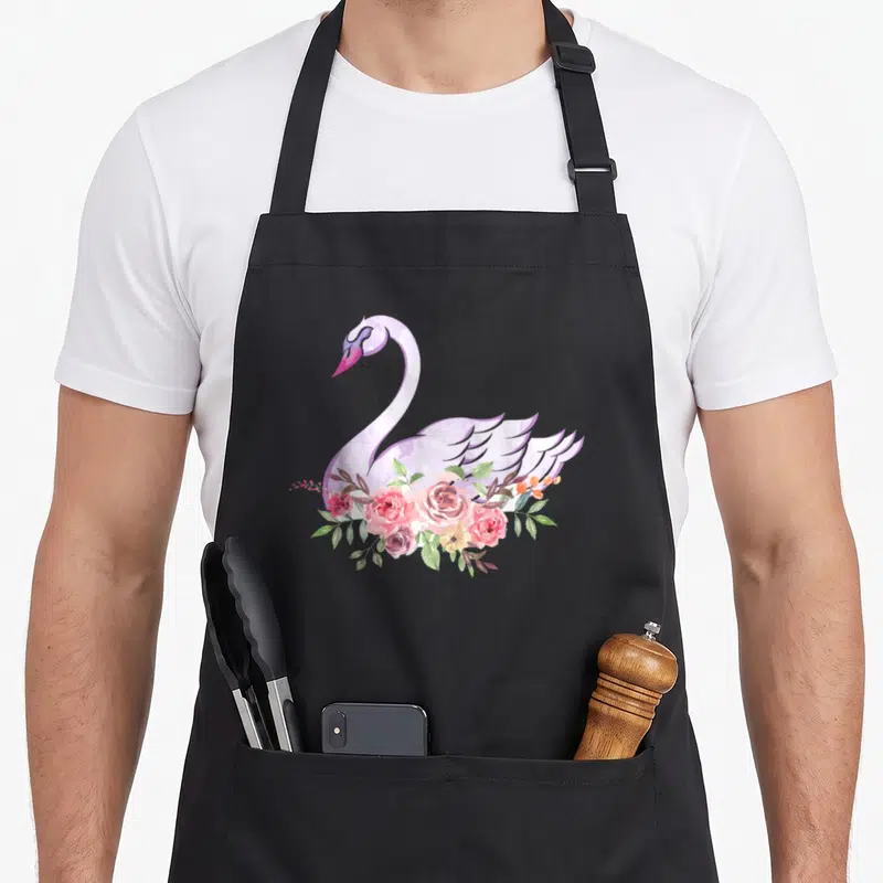 Flower beautiful apron - Watercolor swan in light purple with pink roses and green leaves overlapping its body — shown on a black cotton canvas apron against a white background