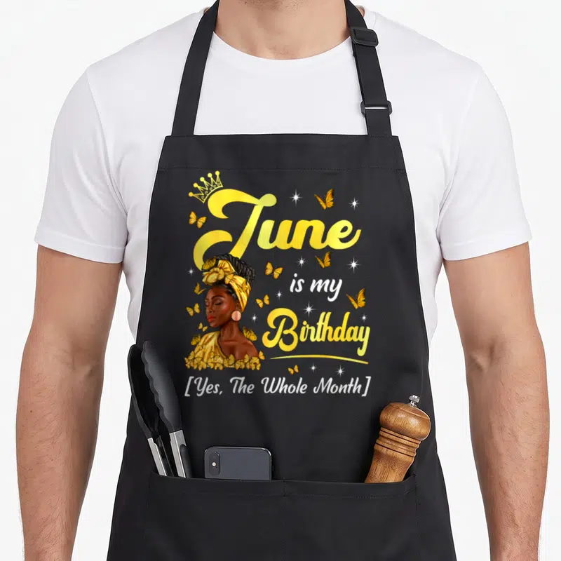 June birthday african american aprons - Cartoon woman with crown and butterflies next to text June is my Birthday Yes — shown on a black cotton canvas apron against a white background