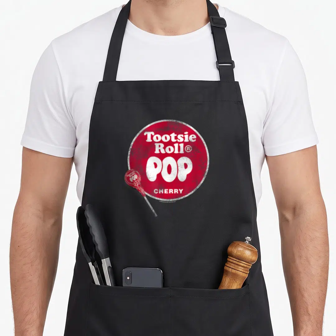 Tootsie candy apron - Distressed red circle with white Tootsie POP CHERRY text and small overlapping lollipop — shown on a black cotton canvas apron against a white background