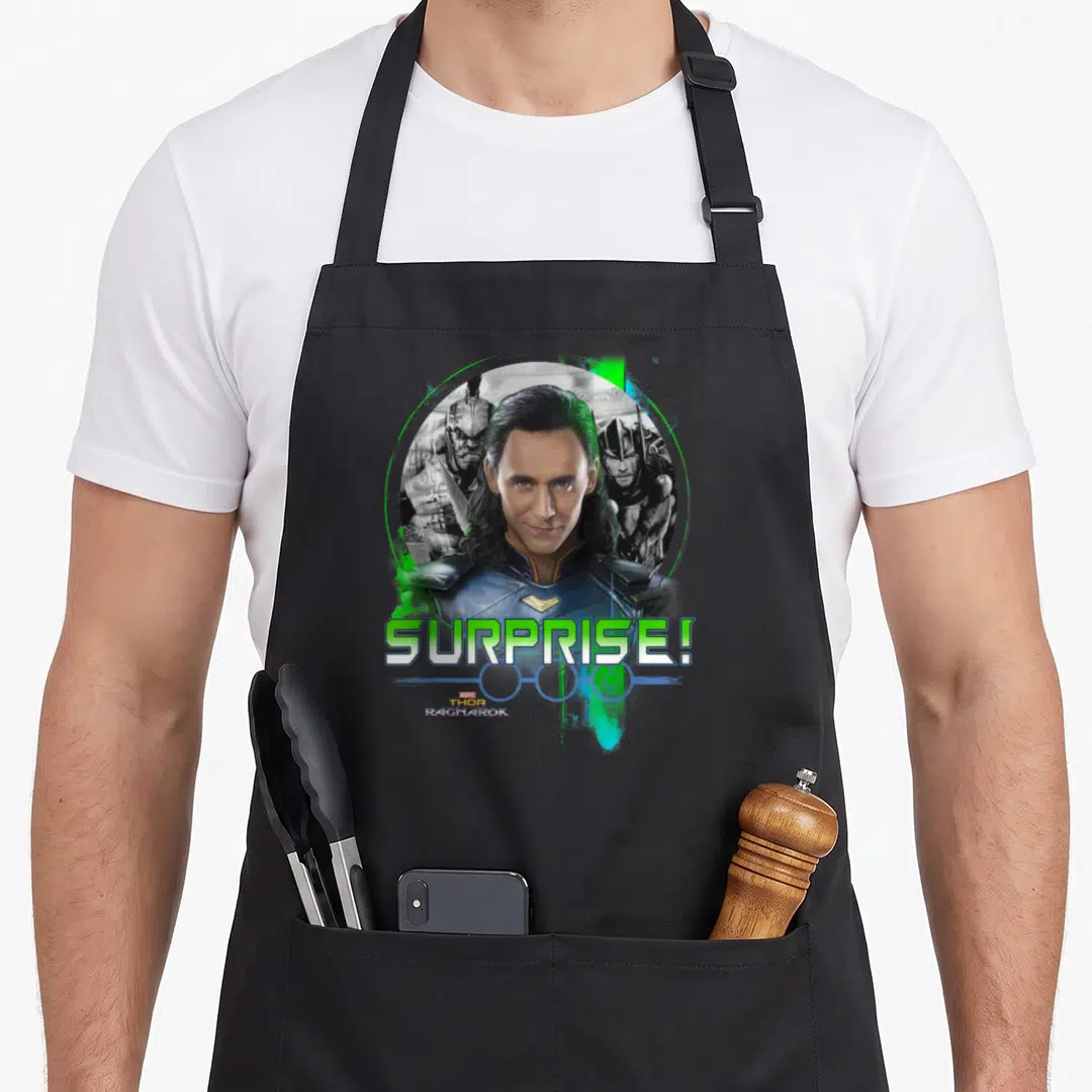Ragnarok collectible apron - Loki centered in lime green circle with Thor Hela behind and SURPRISE text below — shown on a black cotton canvas apron against a white background