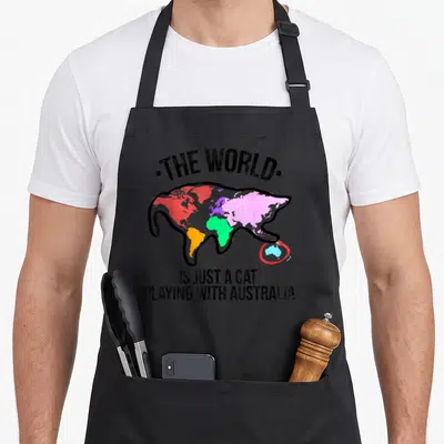 Australia cute cat apron - Cartoon cat world map batting at blue Australia circled in red with black text — shown on a black cotton canvas apron against a white background