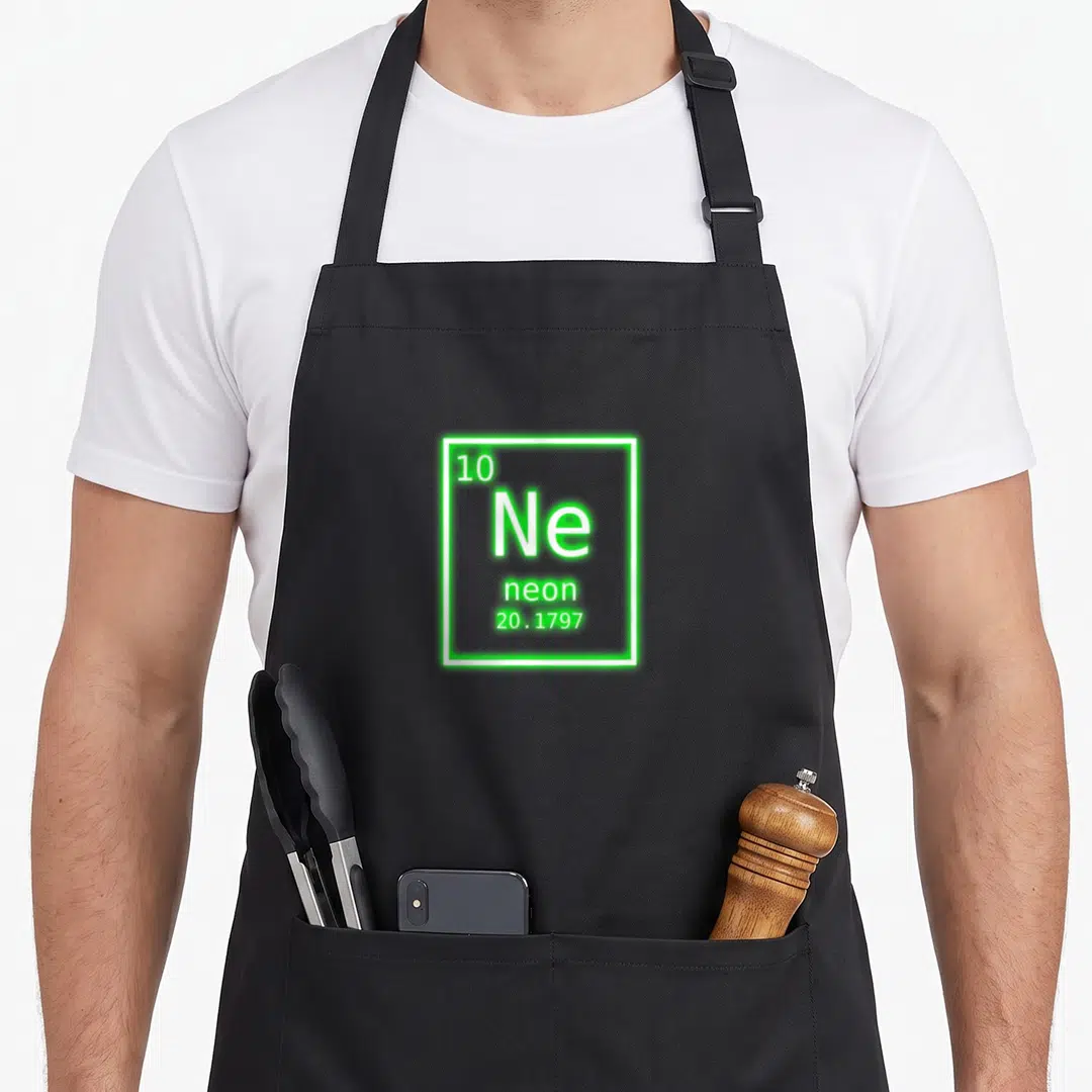Nerd table apron - Periodic table cell for Neon with atomic number 10 and mass 20.1797 in green border — shown on a black cotton canvas apron against a white background