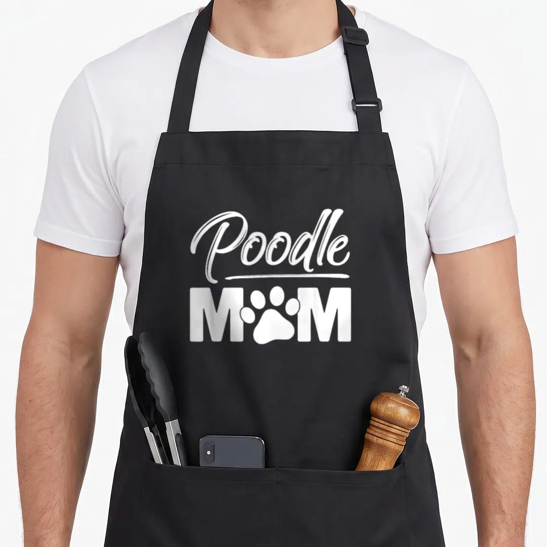 Owner standard size of apron - White Poodle script text above MAM block letters with paw print replacing the O — shown on a black cotton canvas apron against a white background