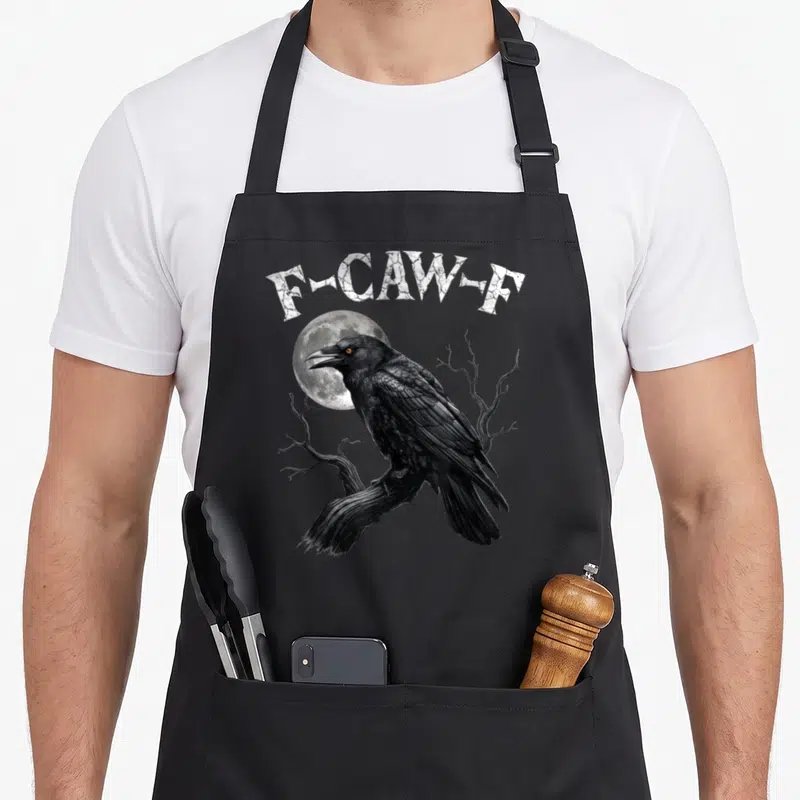 Bird gothic apron - F-CAW-F text above a black crow perched on a branch in front of a moon — shown on a black cotton canvas apron against a white background