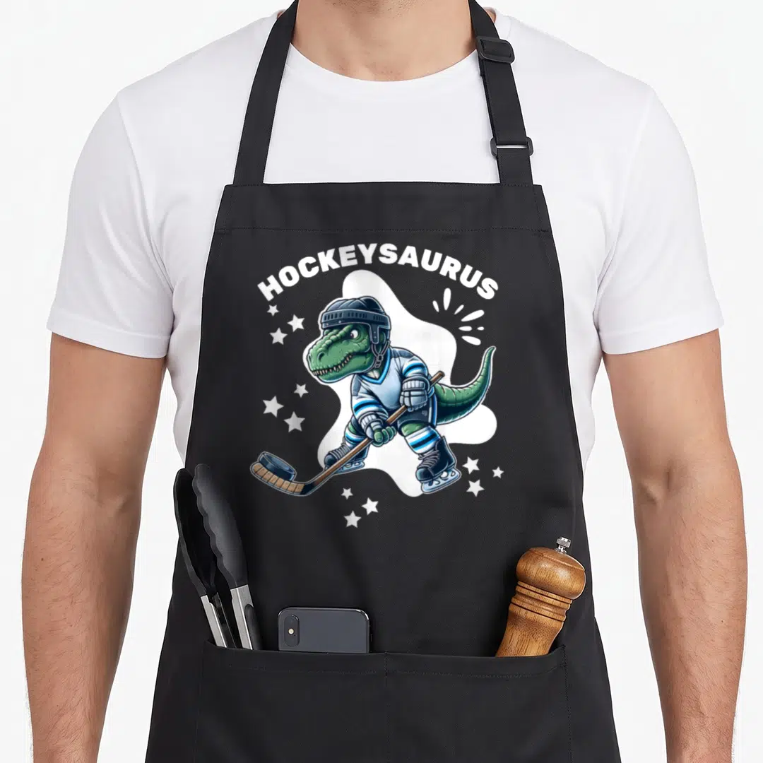 Hockeysaurus hockey hobby apron - Green dinosaur in hockey gear with HOCKEYSAURUS text and stars — shown on a black cotton canvas apron against a white background