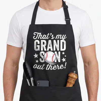 Funny grandson grandma apron - Distressed white text That's my GRAND SON with baseball and stars — shown on a black cotton canvas apron against a white background