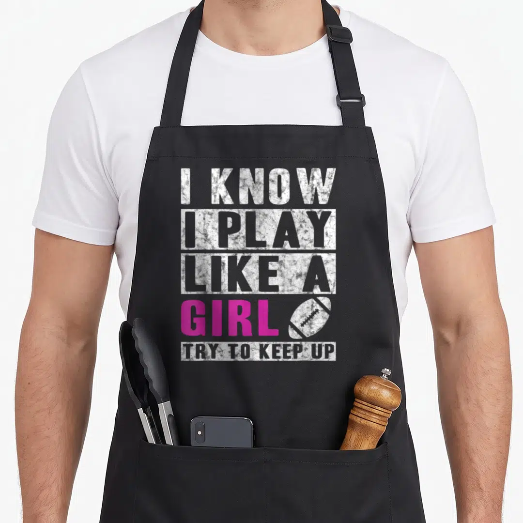 Play football apron - I Know I Play Like A Girl text in white and pink with football icon — shown on a black cotton canvas apron against a white background