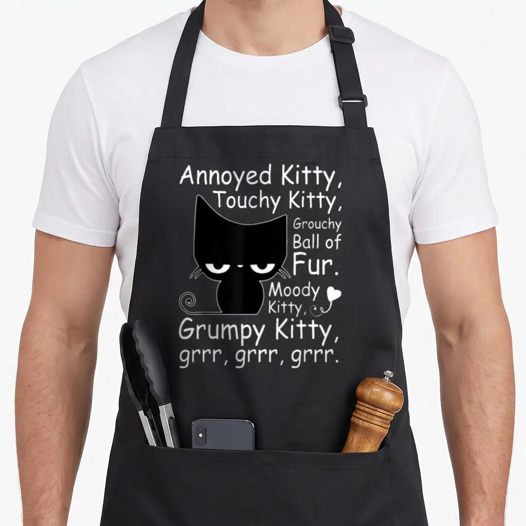 Angry funny cat aprons - Black cat silhouette with Annoyed Kitty text and small white heart — shown on a black cotton canvas apron against a white background