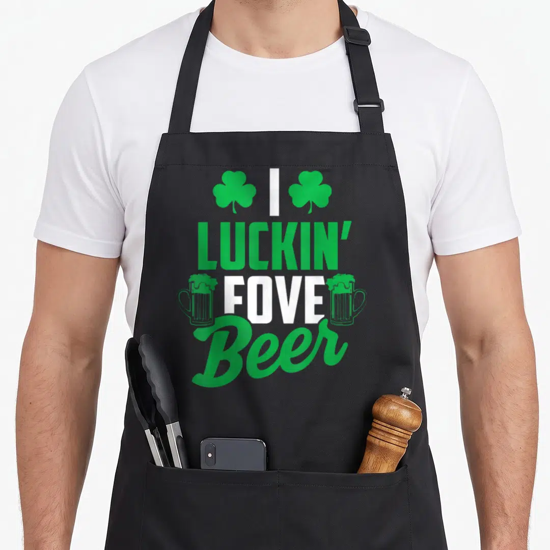 Luckin beer apron - Green white I Luckin Fove Beer text with shamrocks and beer mugs — shown on a black cotton canvas apron against a white background