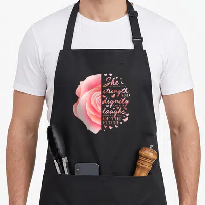 Flower christian apron - Pink rose half and stacked scripture text surrounded by hearts and butterflies — shown on a black cotton canvas apron against a white background