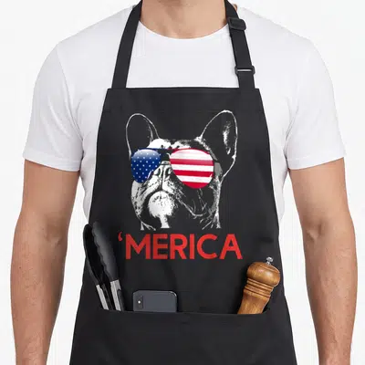 French 4th of july apron - White french bulldog silhouette wearing red white and blue flag sunglasses above red merica — shown on a black cotton canvas apron against a white background