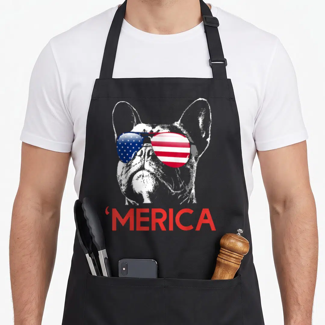 French 4th of july apron - White french bulldog silhouette wearing red white and blue flag sunglasses above red merica — shown on a black cotton canvas apron against a white background
