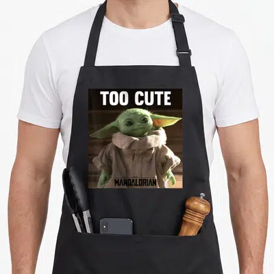 Portrait star war apron - Grogu photo with TOO CUTE text above and THE MANDALORIAN logo below — shown on a black cotton canvas apron against a white background