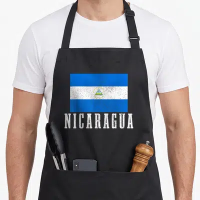 Nicaraguan pride apron - Distressed Nicaragua flag print above white block lettering on black fabric — shown on a black cotton canvas apron against a white background
